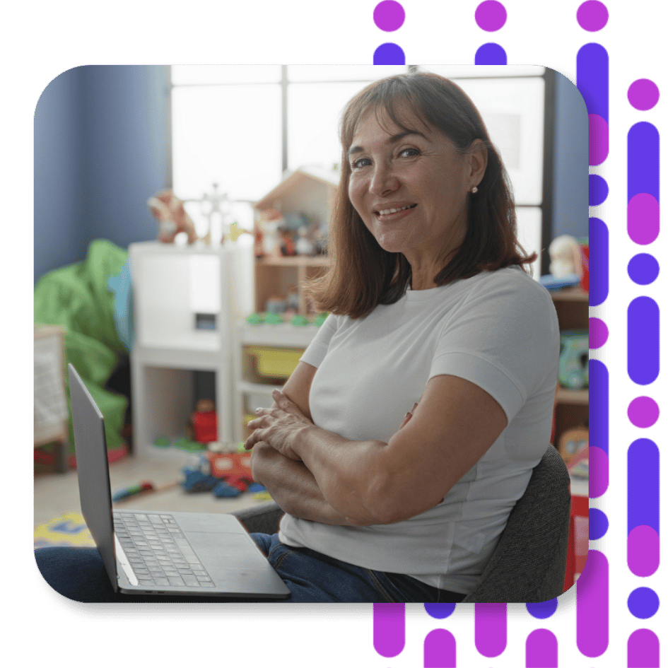 A woman sitting with arms crossed and an open laptop in her lap.